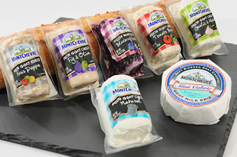 packages of goat cheese against bread on black cutting board