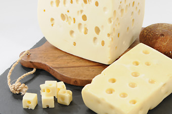 large hunk of cheese on a wooden cutting board