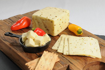 different spicy cheeses and crackers on wooden cutting board