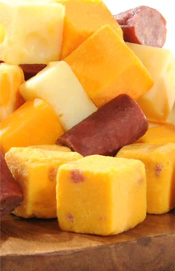 bite-sized cheese and sausage on wooden cutting board